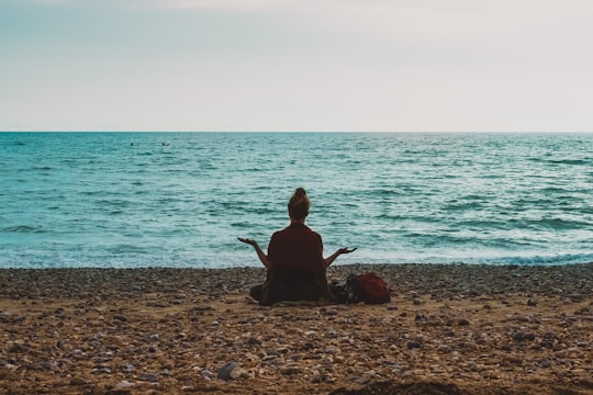 person doing yoga on seashore during daytime in Brighton United Kingdom