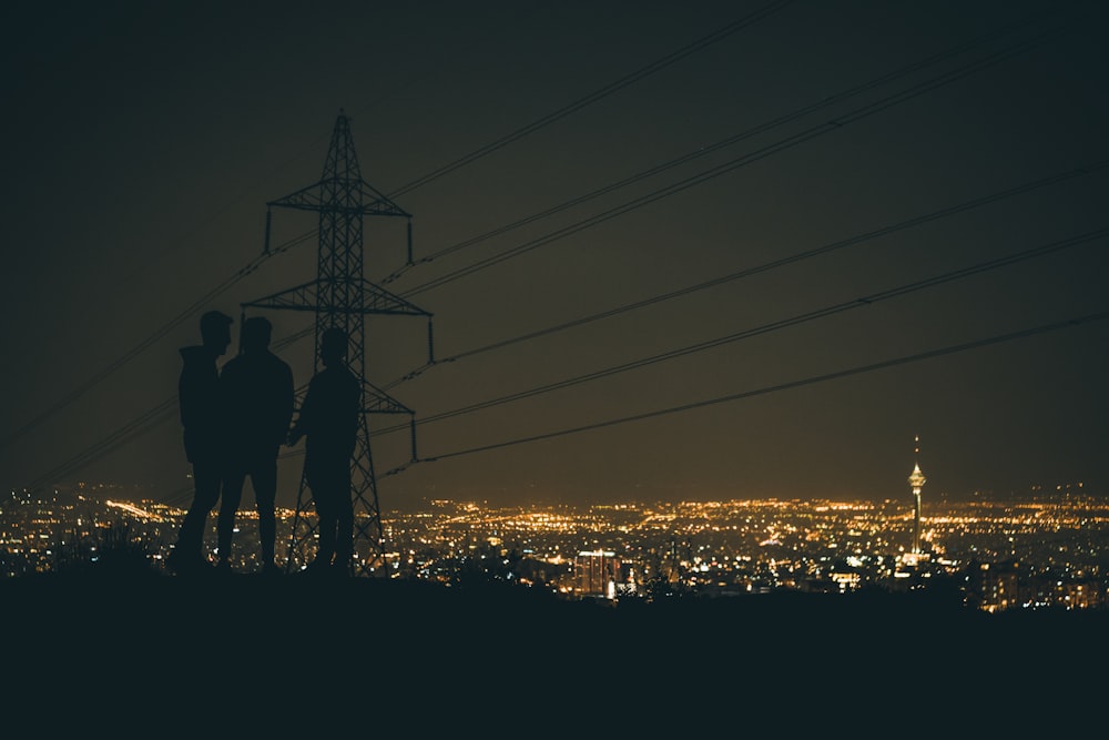 silhouette of 3 people standing near crane