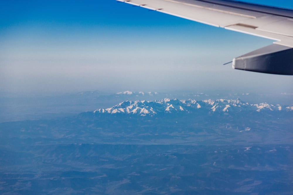 white airplane wing above a snow mountains