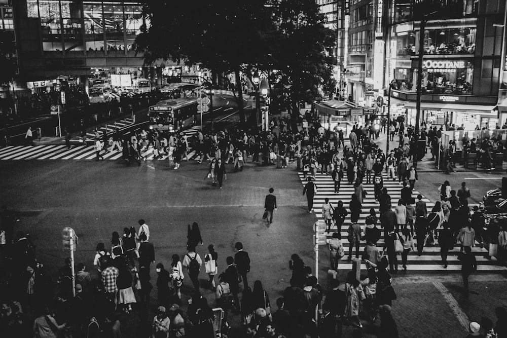 a crowd of people walking across a street at night
