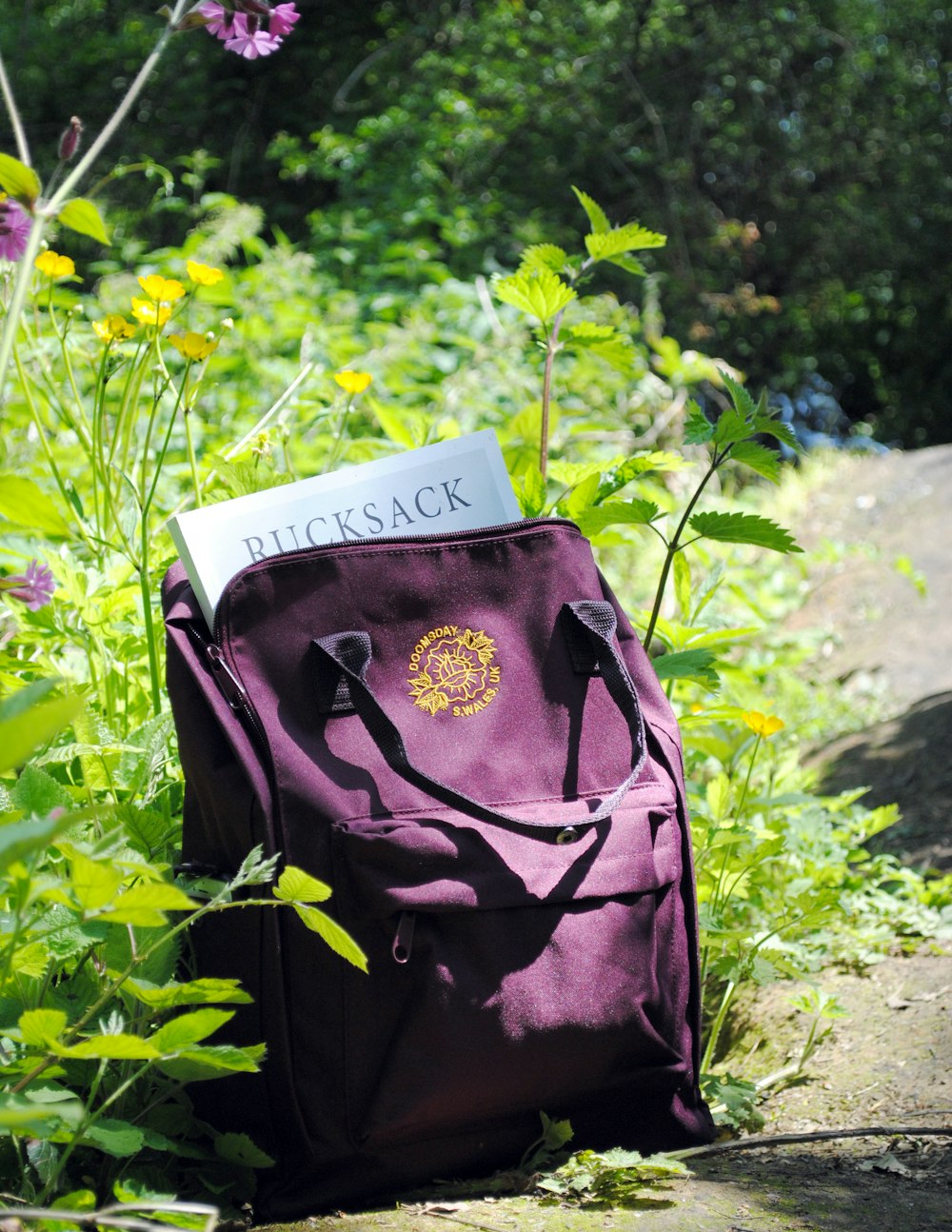 mochila de couro roxo ao lado da flor de pétala