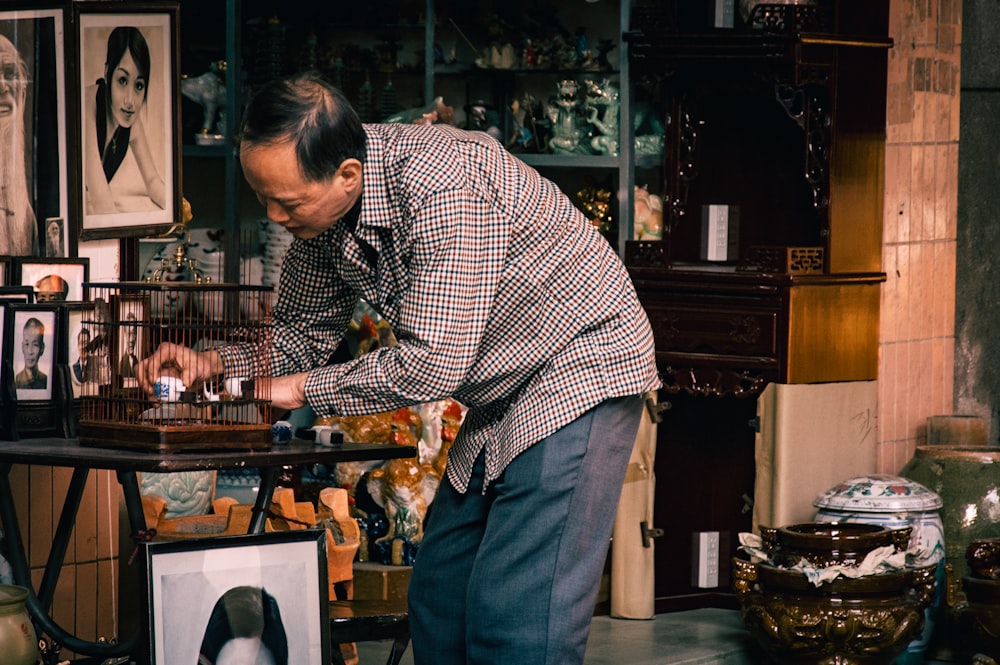 man holding cage artwork on table