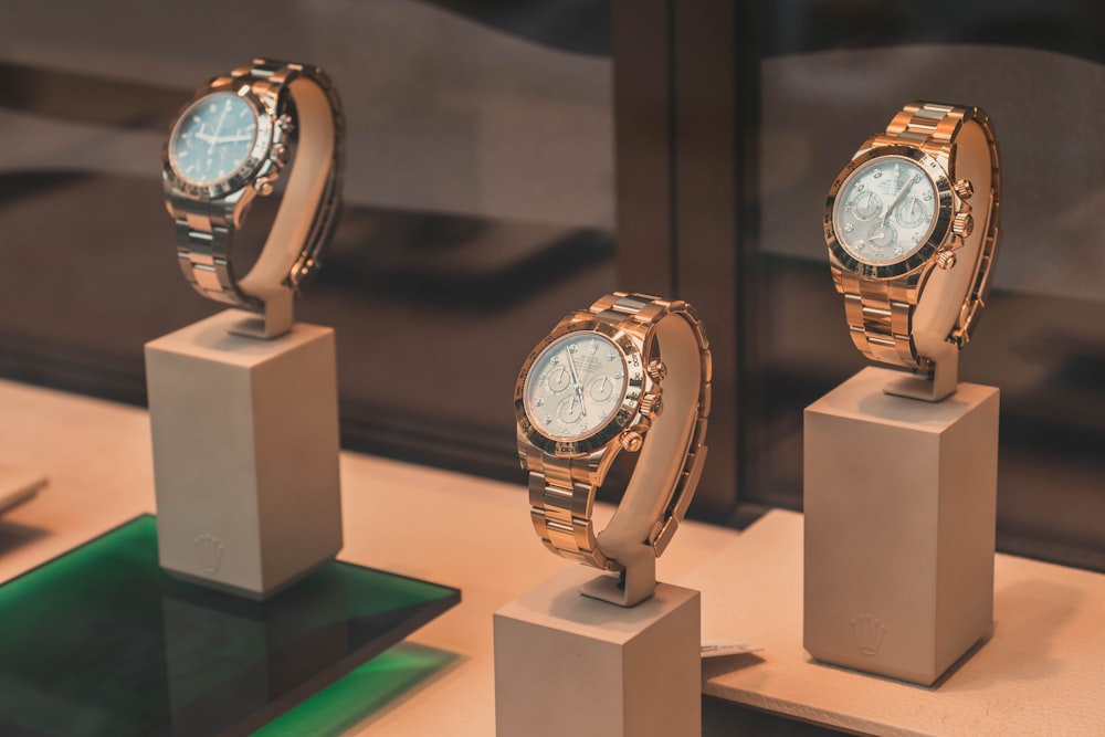 three round silver-colored chronograph watches on white mounts