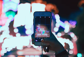 A young creator filming a vibrant short video on their smartphone with colorful neon lights in the background.