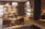 A luxurious shoe store interior with wooden walls and shelves displaying various designer shoes. There are comfortable leather chairs and a small wooden table placed in the center. The room has warm lighting and a clean, organized arrangement, creating a sophisticated atmosphere.