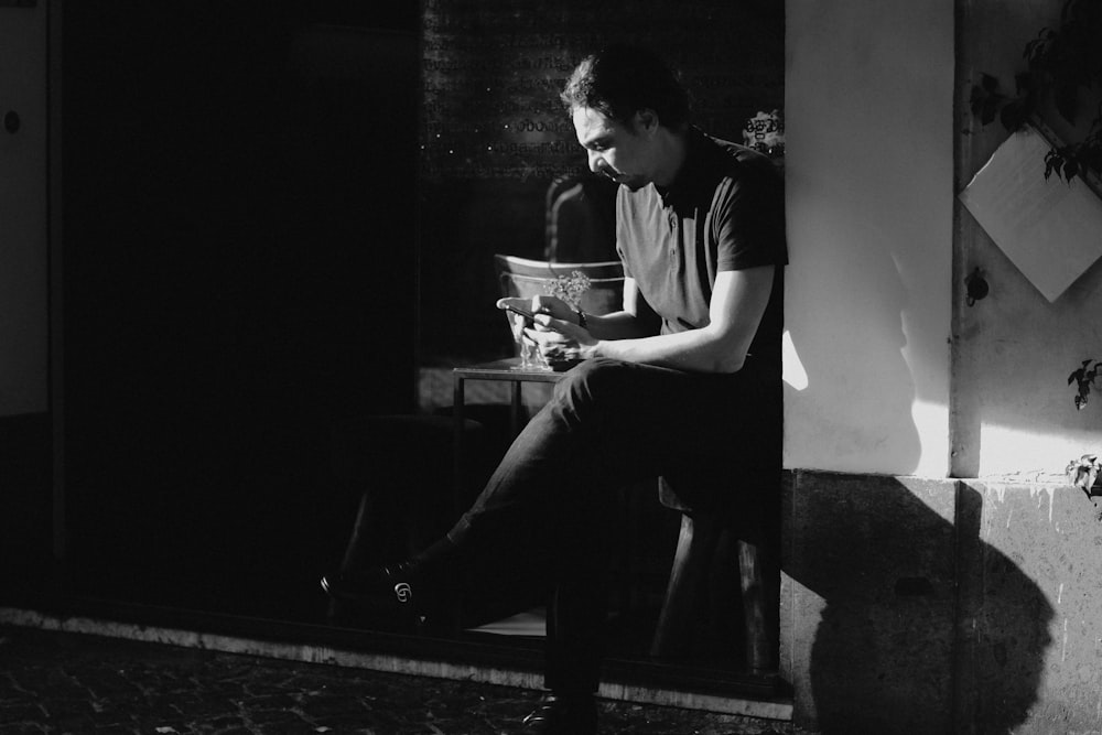 grayscale photography of man sitting beside table