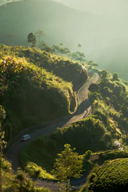 A comfortable vehicle winding through lush green valleys on a sunny day.