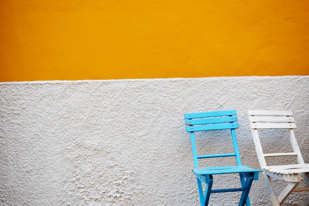 cadeiras de madeira azul e branca ao lado da parede