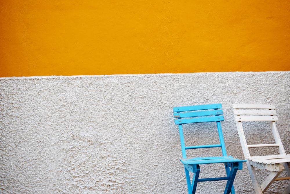 Sillas de madera azules y blancas al lado de la pared