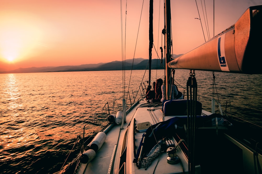 Weißes und schwarzes Segelboot bei Sonnenuntergang