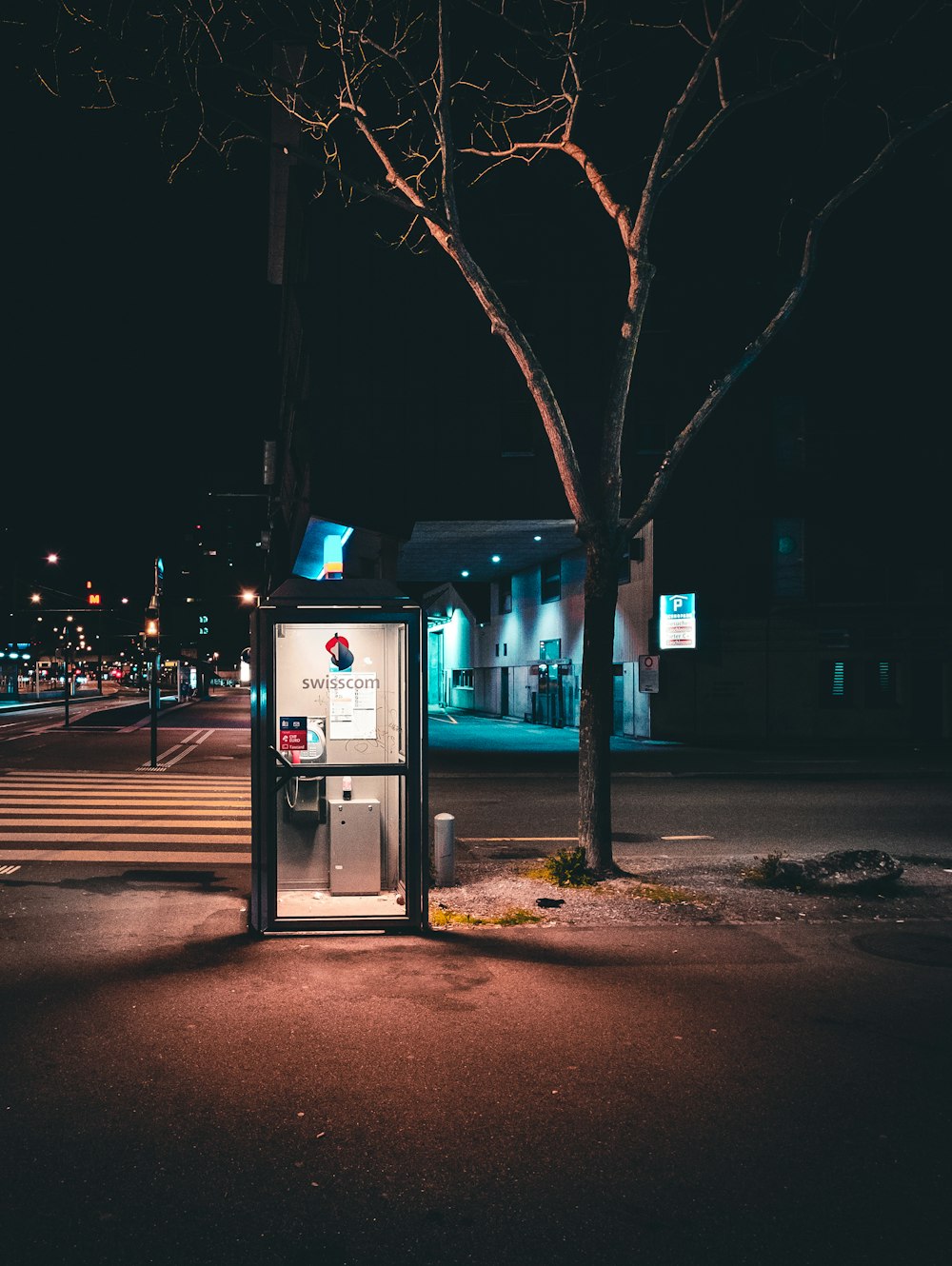 black lighted telephone booth near tree at nighttime photography