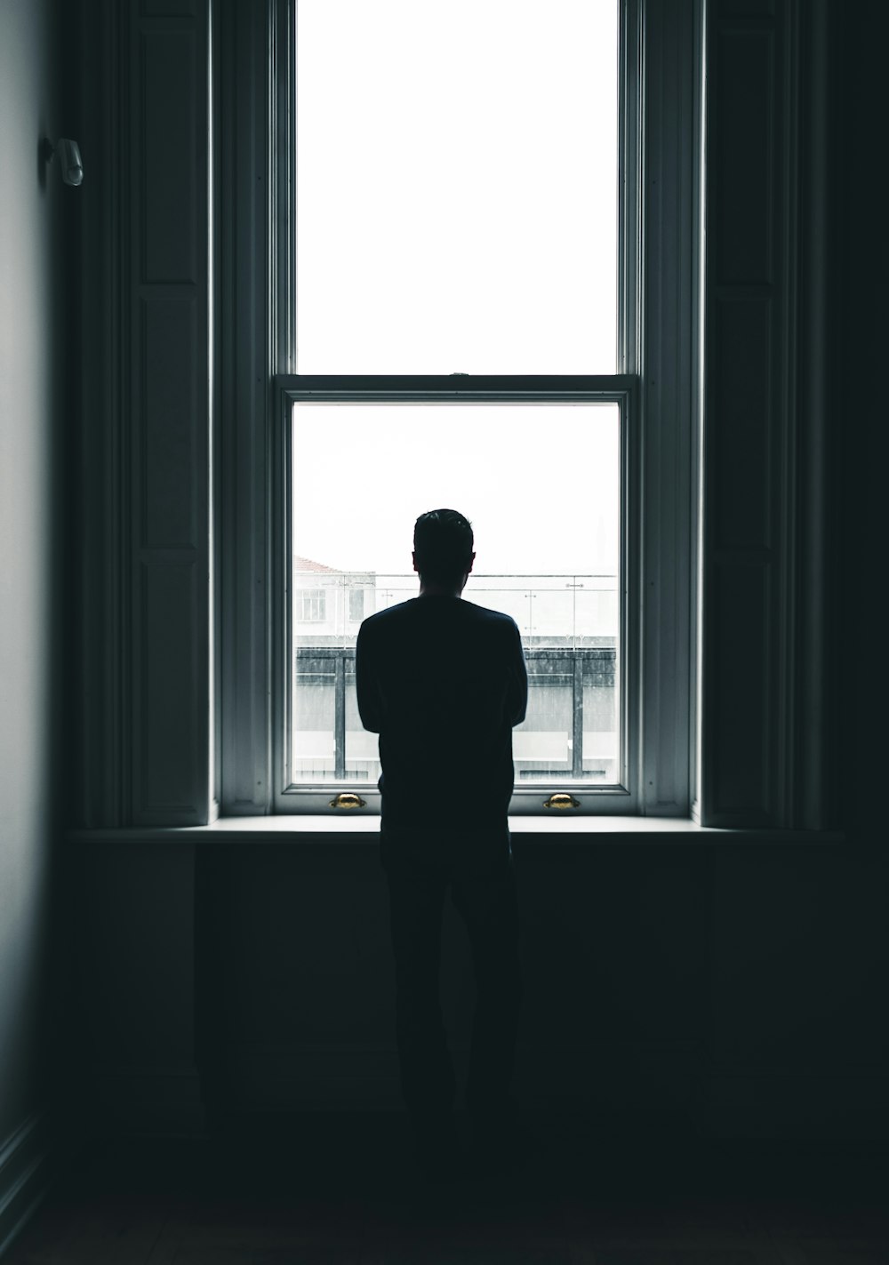Silhouette einer Person, die tagsüber vor dem Fenster steht