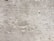 A textured concrete wall with noticeable wear and small holes throughout the surface. There are visible grooves and lines, likely from the construction process.