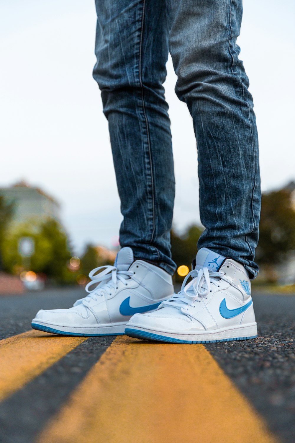 fotografia de foco seletivo de pessoa vestindo azul e branco Nike Air Jordan 1