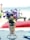 A bouquet of colorful artificial flowers in a woven basket-like holder is placed on a table. The background features a sandy beach and the ocean. A blurred person in swimwear and beach chairs can be seen, indicating a relaxed beach setting.