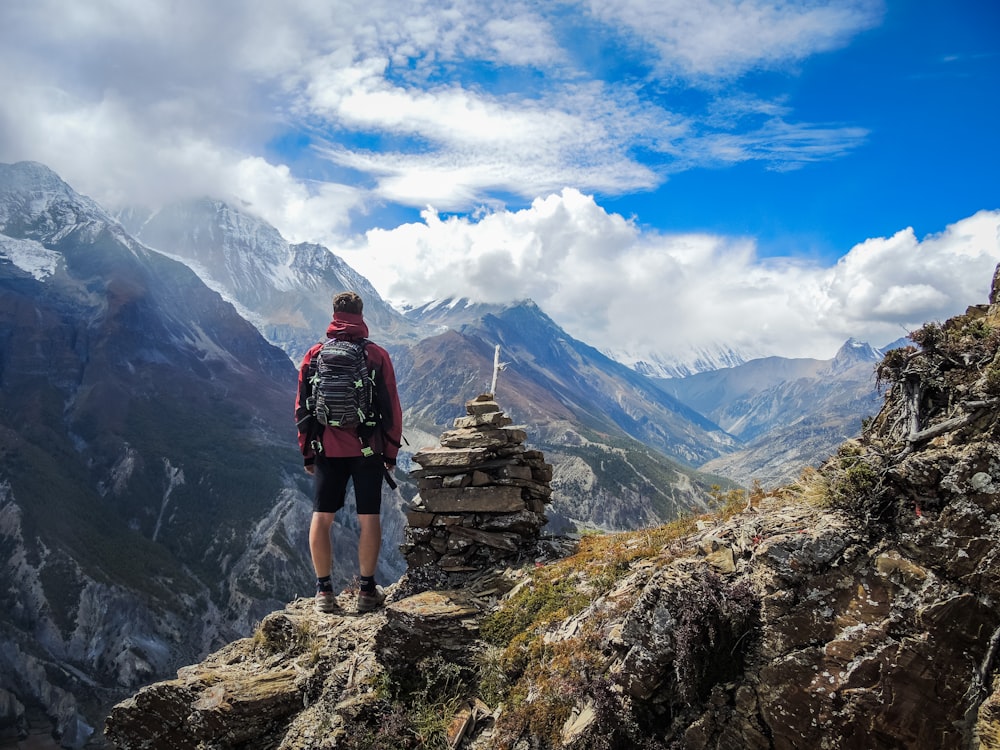 Homme debout au sommet d’une montagne à côté de pierres de cairn