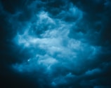 Dark clouds form a dense, swirling pattern in the sky, suggesting the onset of a storm. The texture is dramatic and turbulent, with shades of blue and gray blending together.