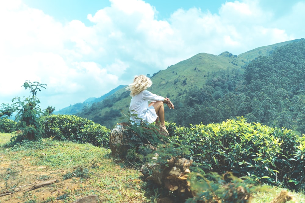 woman sitting on rock near mountain range