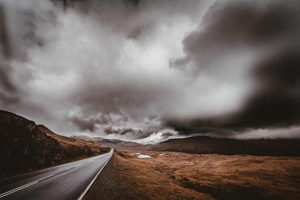 gray asphalt road beside brown rock formations