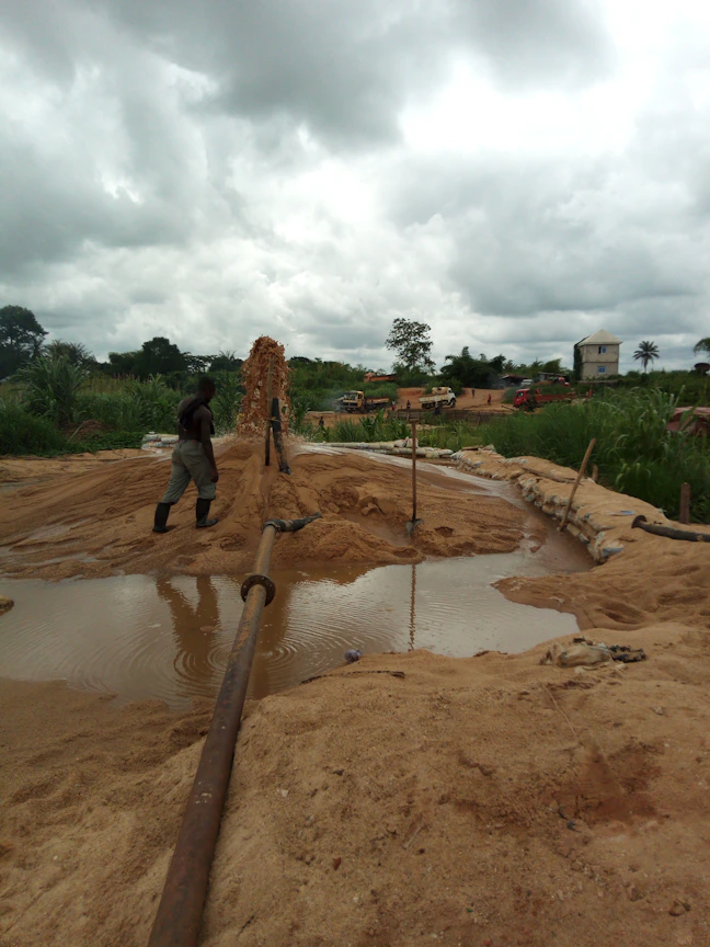 Professional engineer inspecting hydraulic network plans at a construction site with water pipes and equipment visible.