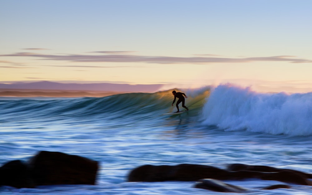 uomo che fa surf all'oceano durante il tramonto