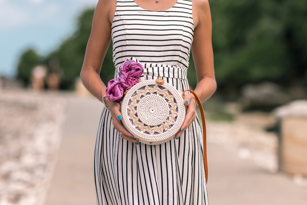 donna che indossa un vestito a righe bianche e nere che tiene una borsa bianca e marrone