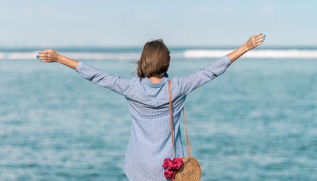 woman spreading hands standing near body of water