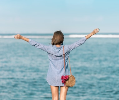 woman spreading hands standing near body of water