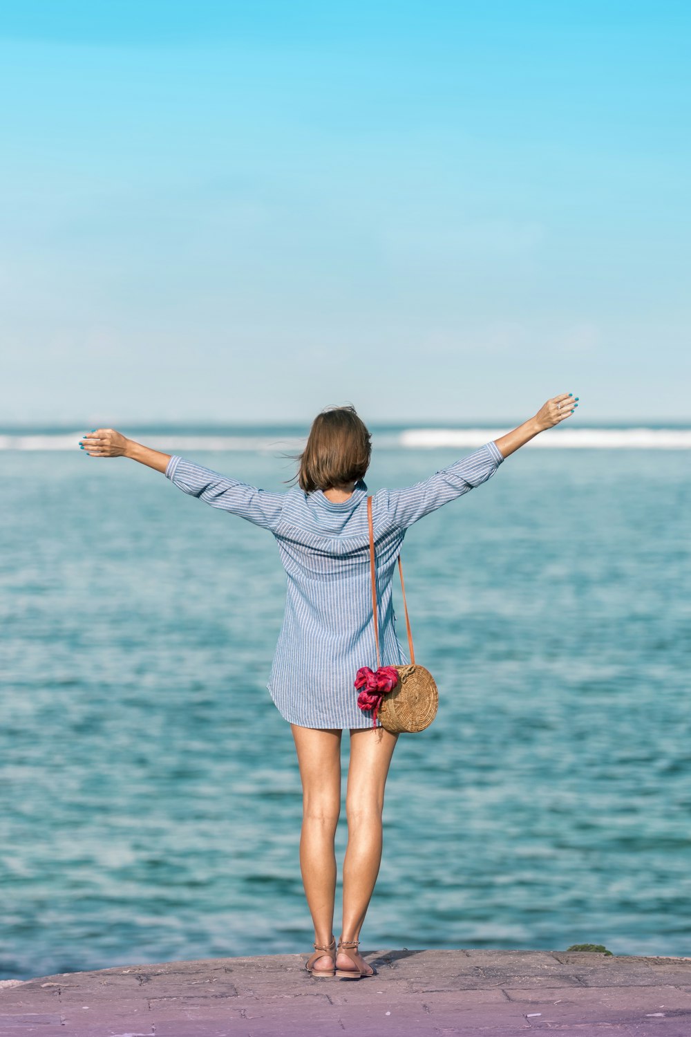 woman spreading hands standing near body of water