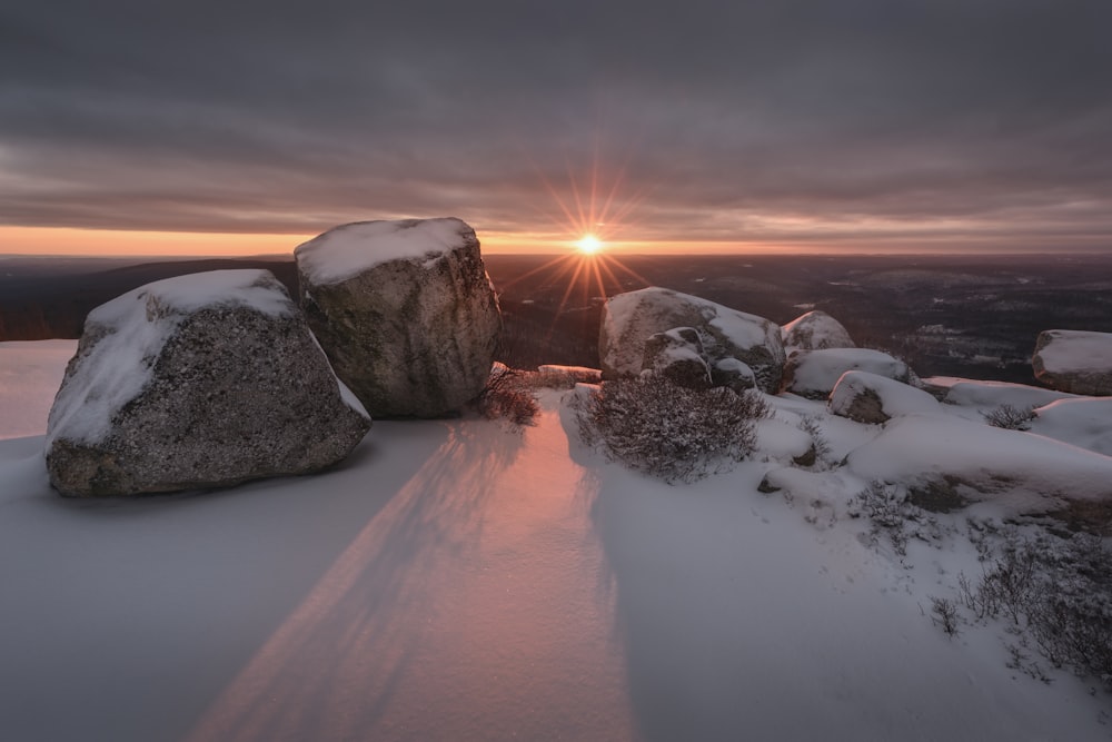 snow covered rocks against golden sun