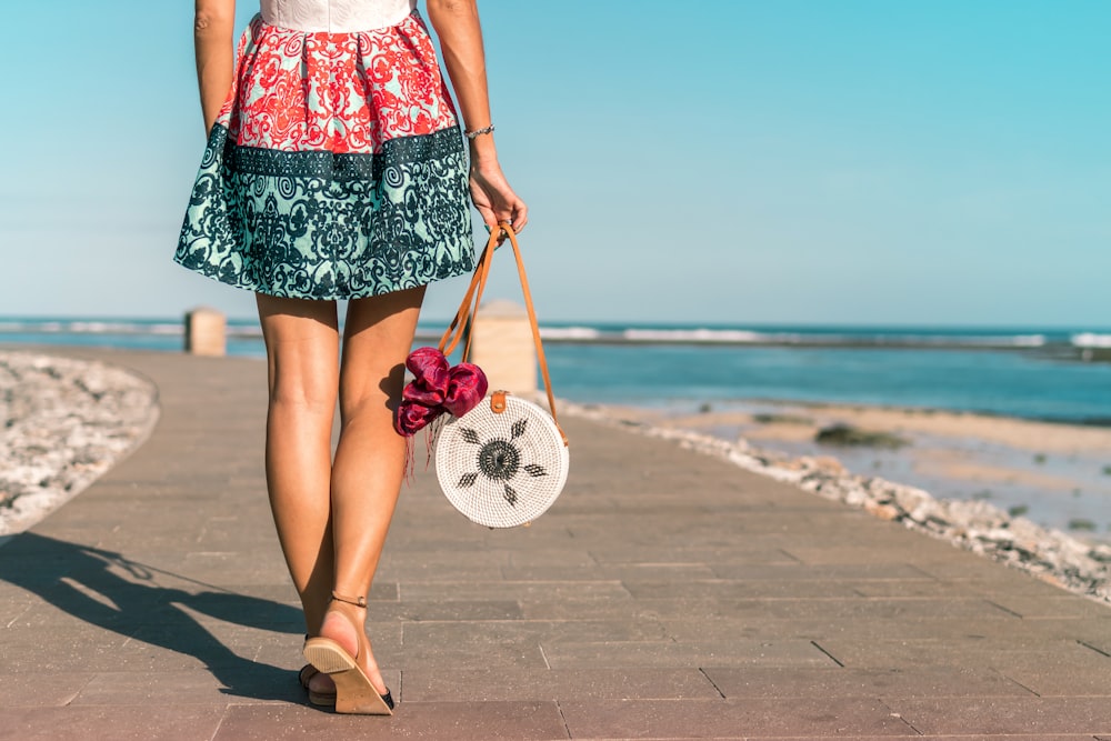 femme portant un sac blanc tout en marchant sur un chemin gris