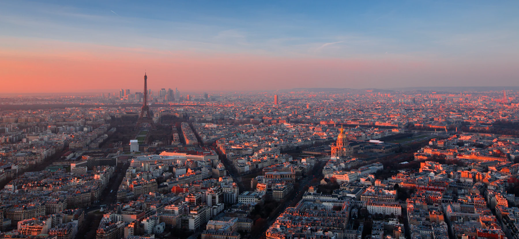 Aerial view of Paris rooftops at golden hour with the Eiffel Tower on the skyline