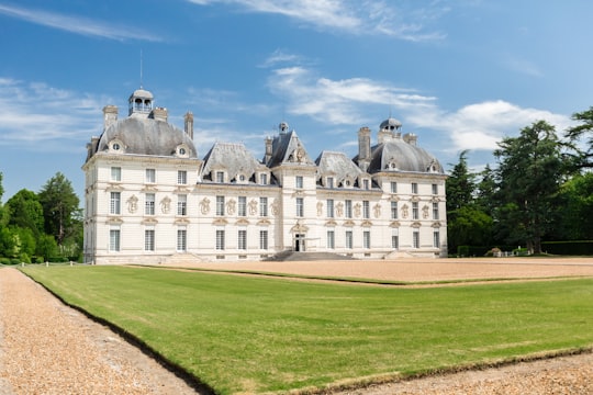 white and gray concrete building near green lawn under blue sky during daytime in Château de Cheverny France