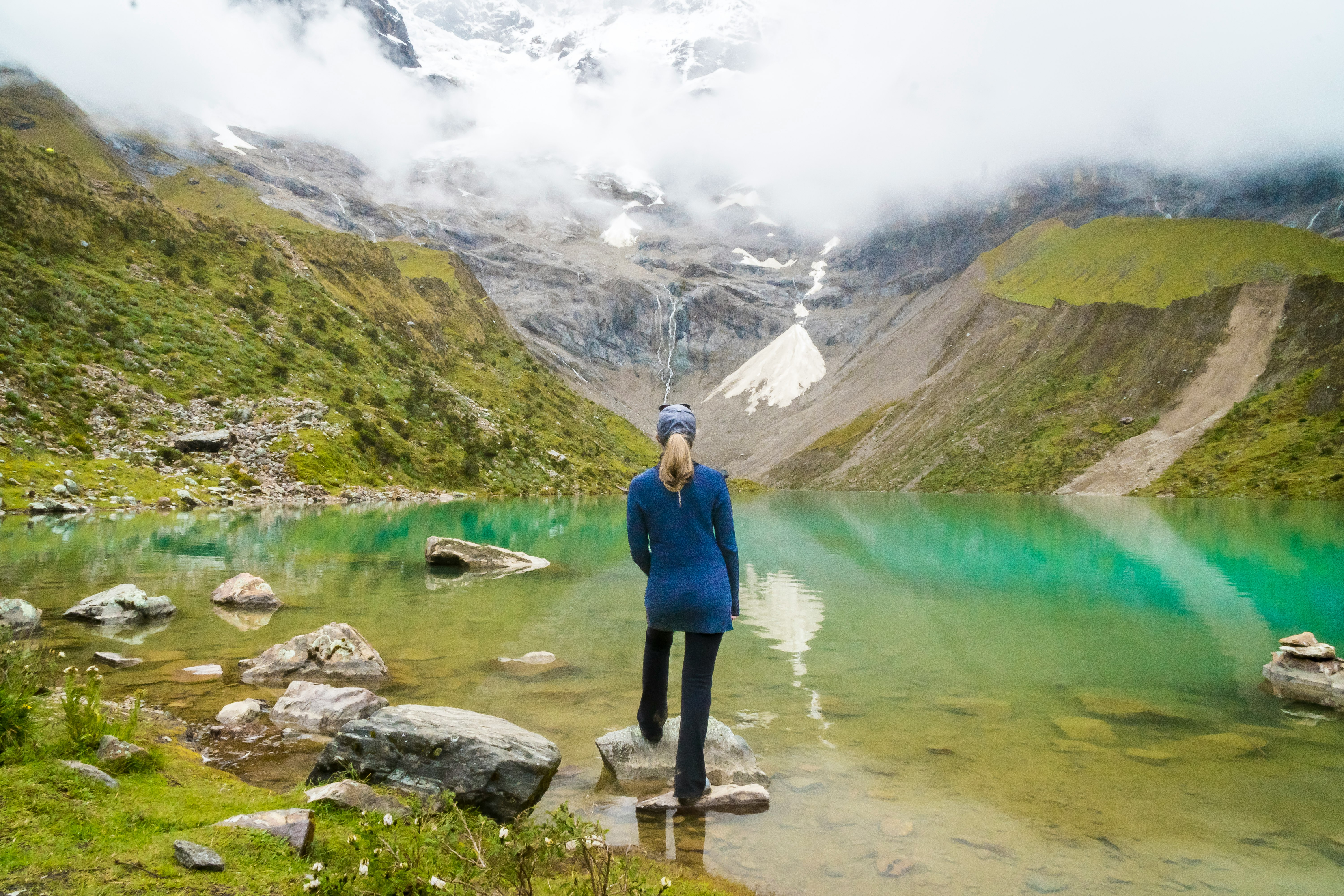 woman standing in front of body of water and mountain