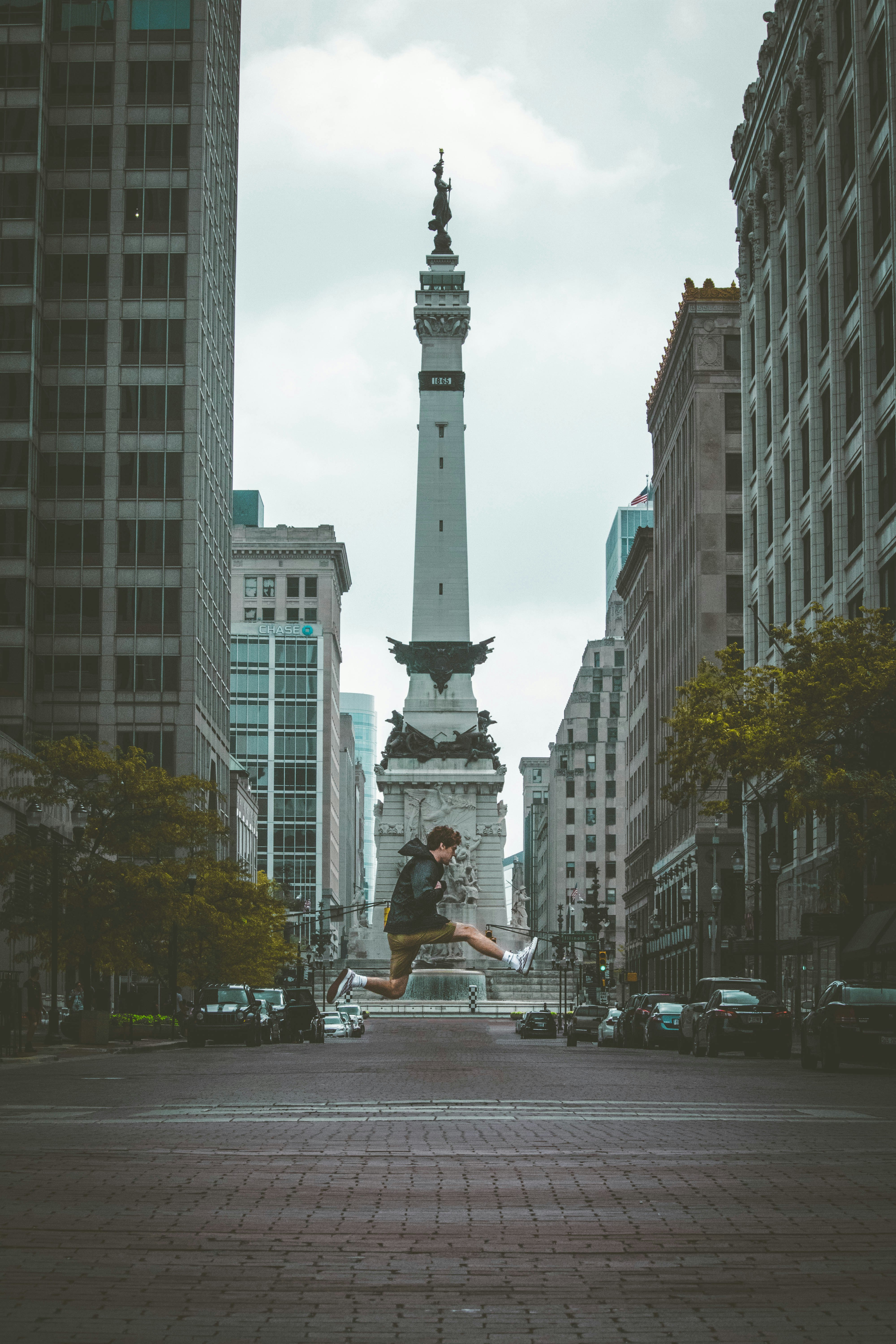 jump shot photo of man with monument background between buildings
