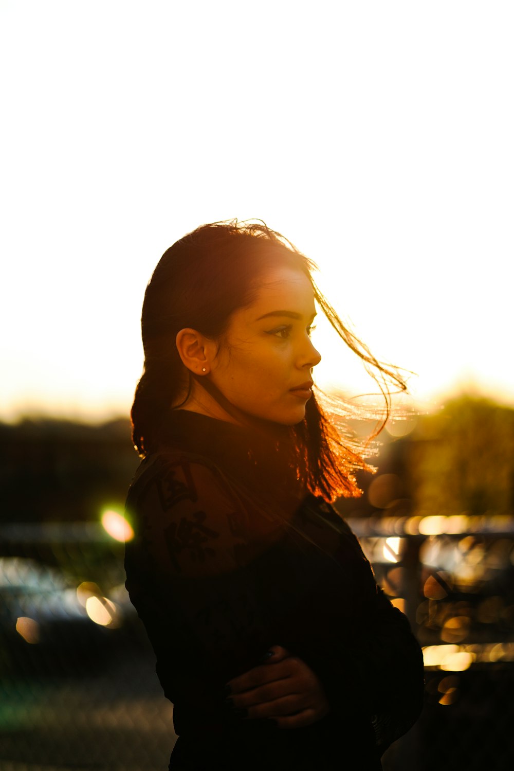 femme debout devant une clôture en métal gris au coucher du soleil