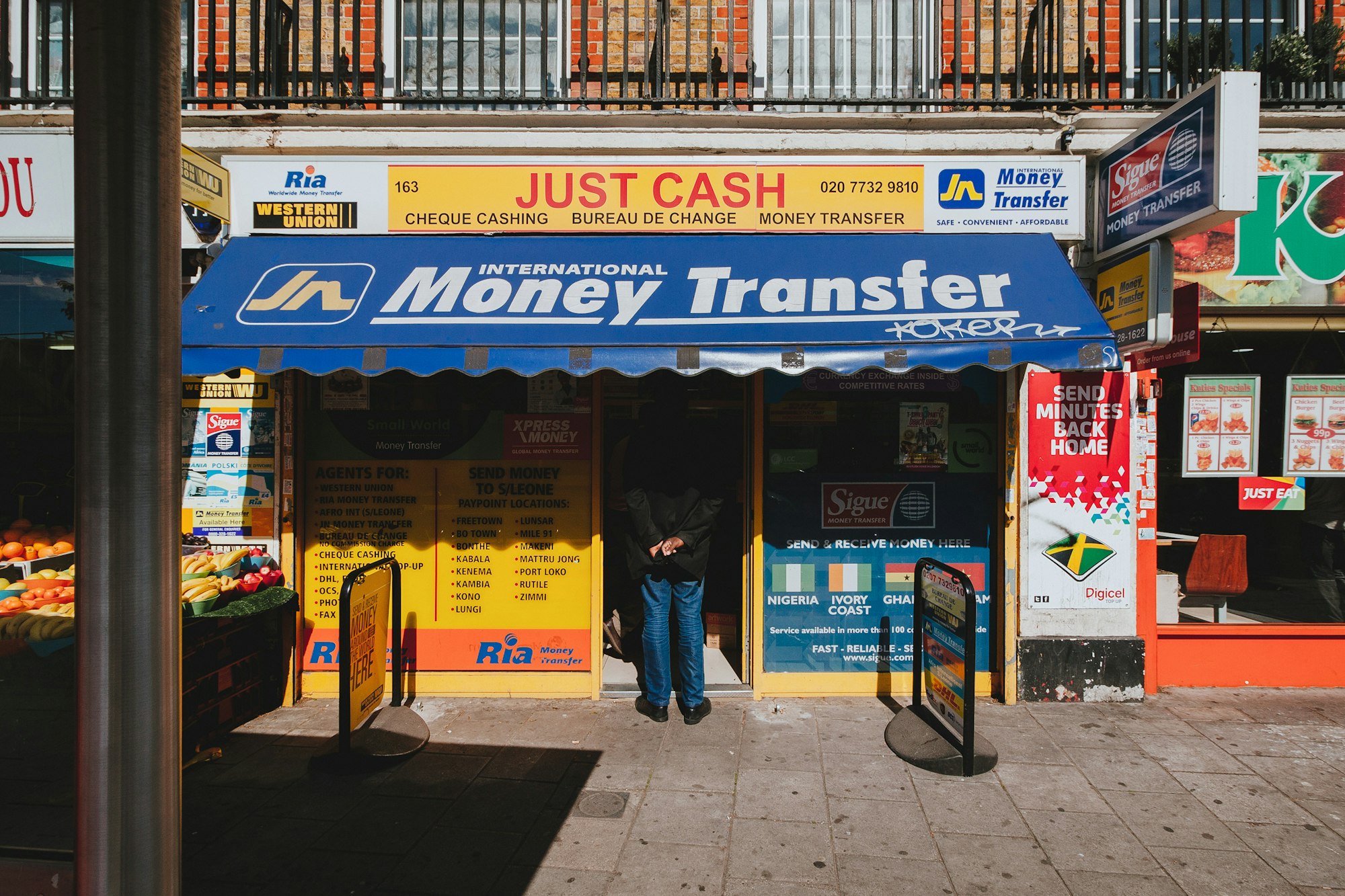 Street scene of a man waiting in line at a money transfer shop in London, notoriously dodgy places.