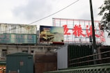 Billboards and signs in an outdoor setting display both English and Chinese text. The prominent sign advertises the Sea King Garden Restaurant, while another sign features an image of a restaurant by water at night.
