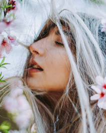 Softly lit close-up of flowing hair with delicate flower petals resting gently on strands.