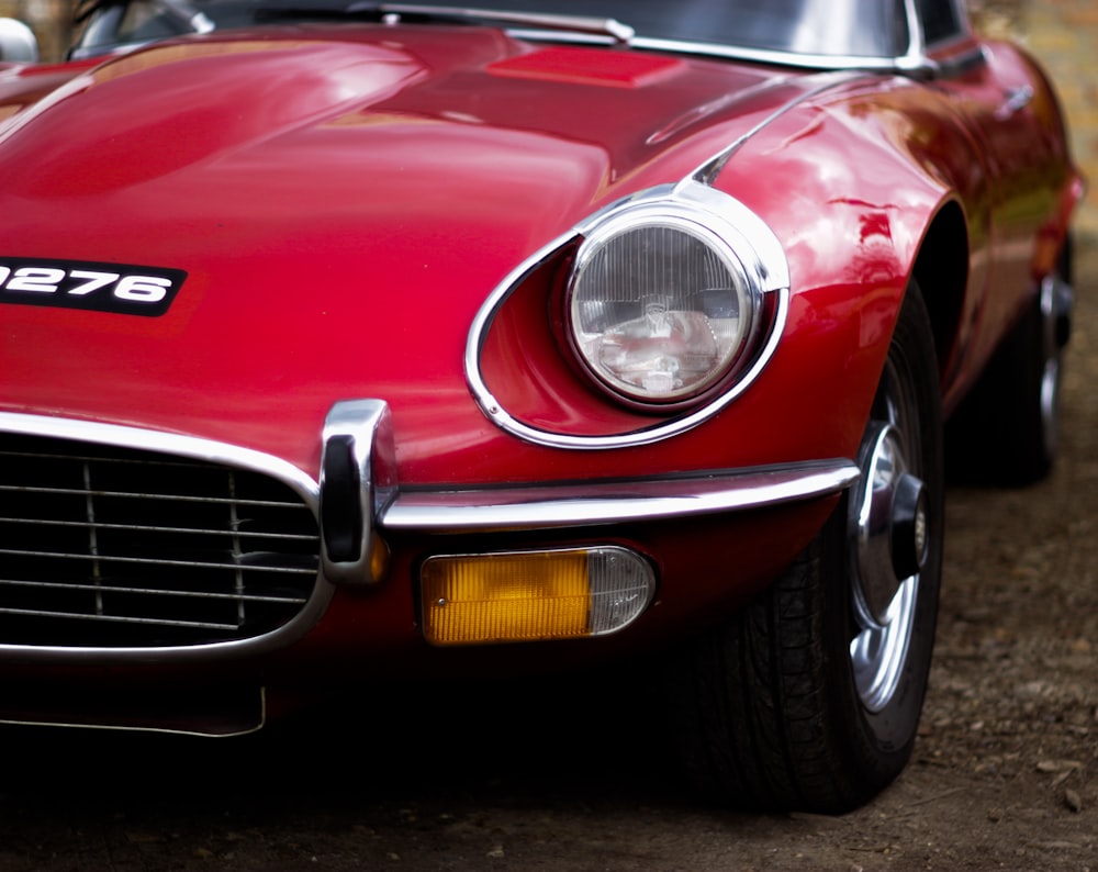 red coupe parked on brown soil