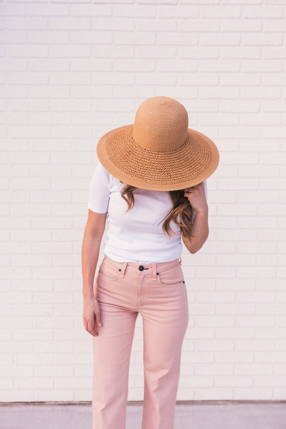 Woman wearing white shirt, pink pants, and brown sun hat photo