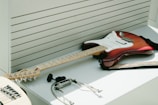 A sleek electric guitar resting on a stand with studio monitors in the background