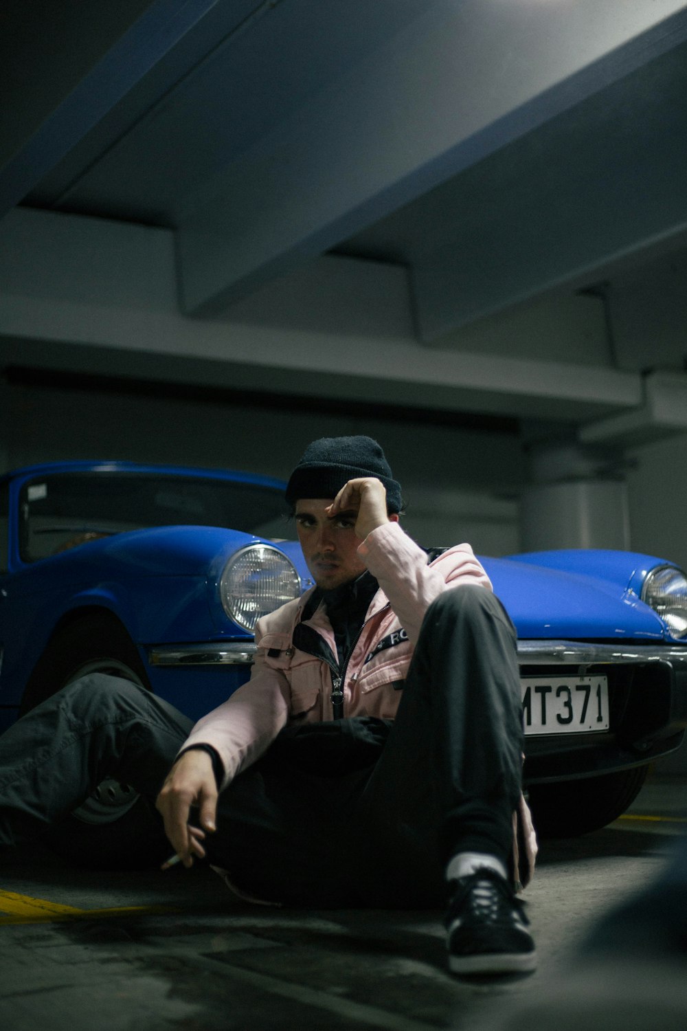 man sitting near blue car