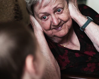 A caring support worker gently assisting an elderly woman with daily grooming in a bright, cozy home setting.