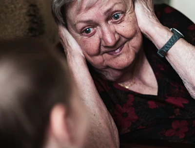 A caring support worker gently assisting an elderly woman with daily grooming in a bright, cozy home setting.