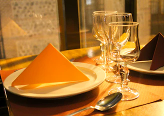 A neatly stacked set of dinner napkins beside a warmly lit dining table setting.