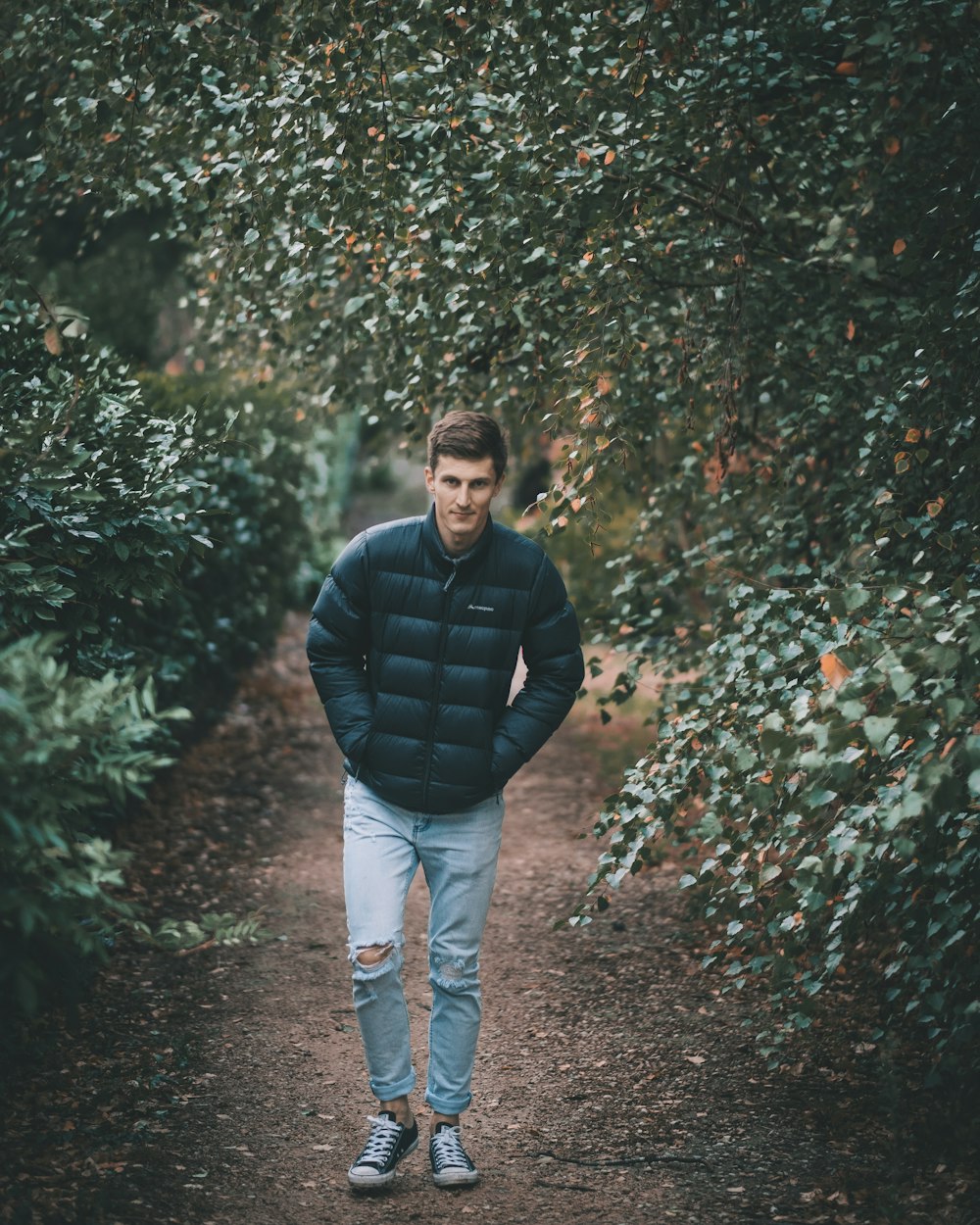 man wearing puffer jacket between trees