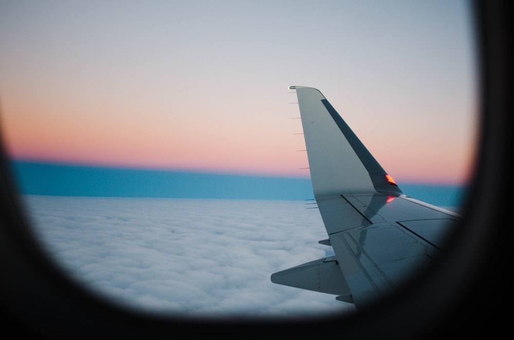 white airplane wing above white clouds