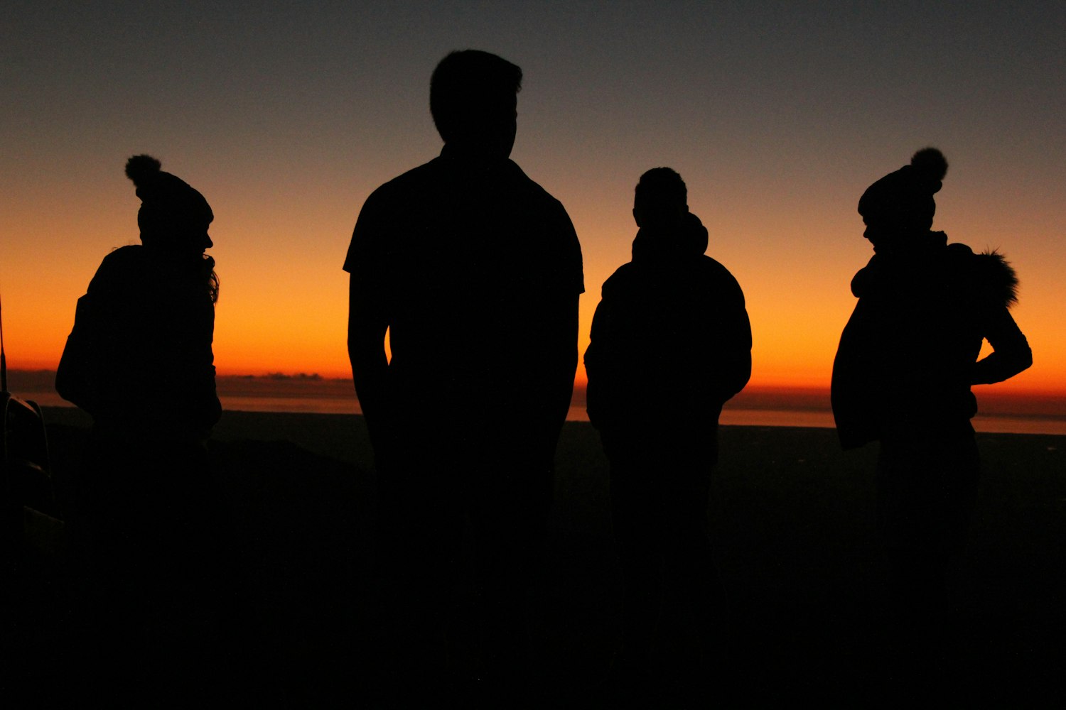 silhouette of four persons standing during sunset