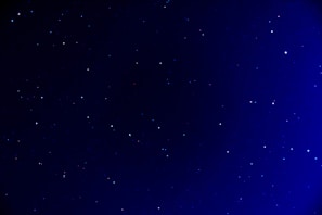 A deep blue night sky scattered with numerous small stars, creating a serene and expansive view of the universe.